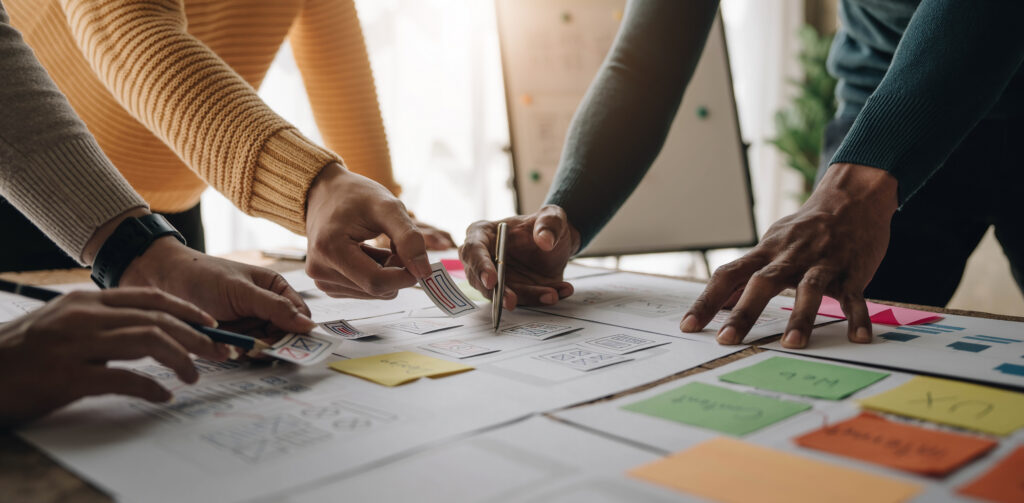 Close up ux developer and ui designer brainstorming about mobile app interface wireframe design on table with customer breif and color code at modern office.Creative digital development agency.