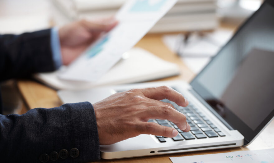 Close-up image of businessman checking documents and working on laptop, selective focus