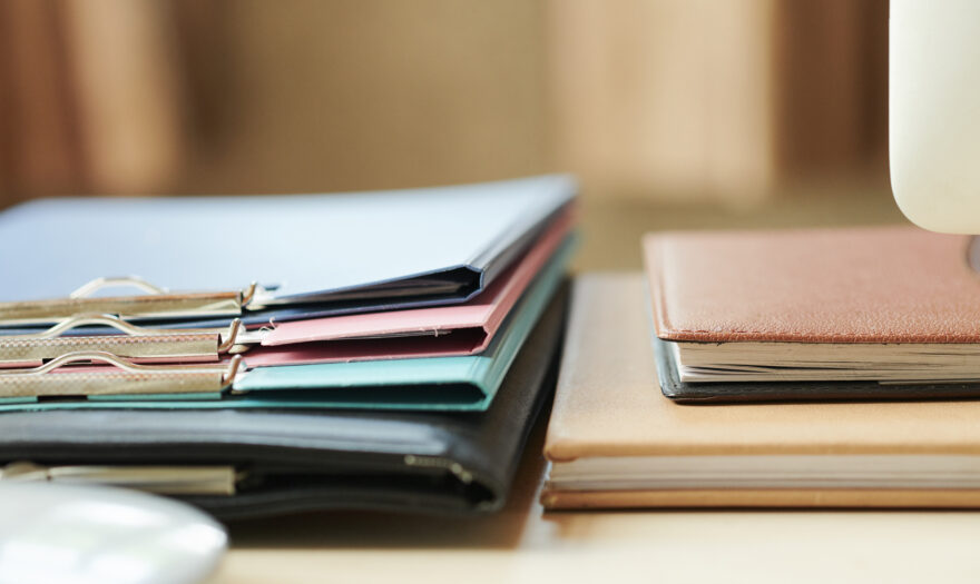 Stack of folders and planners on office desk, selective focus