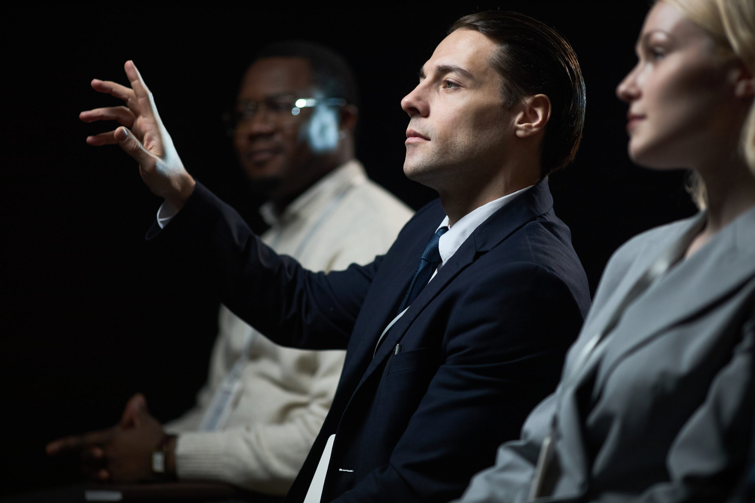 Caucasian businessman gesturing while speaking during panel discussion with diverse colleagues, presenting leadership and teamwork concepts. Useful for corporate communication or business event marketing
